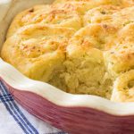 Soft savory dinner rolls filled with garlic, Parmesan cheese, and basil in a baking dish.