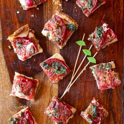 This Tomato Caprese Tart is easy to make with fresh peak season tomatoes, mozzarella cheese, and a pesto - all tucked into a tart shell. Use it for an appetizer, side dish or vegetarian dinner.