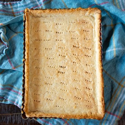 This Tomato Caprese Tart is easy to make with fresh peak season tomatoes, mozzarella cheese, and a pesto - all tucked into a tart shell. Use it for an appetizer, side dish or vegetarian dinner.
