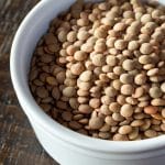 A white ramekin filled with brown lentils.