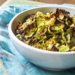 A bowl of crispy Brussels sprouts chips dusted with nutritional yeast.