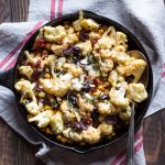 Warm cauliflower salad with sundried tomatoes, kalamata olives, and crispy chickpeas all tossed in a miso dressing. It's all in a cast iron skillet.