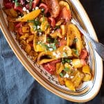 Bell peppers roasted in the air fryer are arrange in a serving dish with basil, capers and feta.