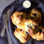 Peach and blueberry drop biscuits piled in a basket with a ramekin of butter.