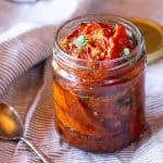 A jar of balsamic roasted tomatoes and olive oil for preserving.