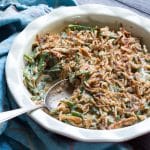 Green bean casserole topped with fried onion rings in a baking dish.