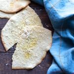 Slices of piadine flatbreads topped with olive oil and Parmesan cheese.