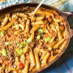 Skillet with ziti pasta and cheese sauce, diced tomato, topped with cilantro.