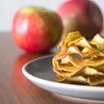 Baked apple slices dusted with curry powder, stacked on a plate.