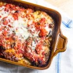 An eggplant parmesan casserole with pesto in a casserole baking dish.