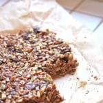 A slab of granola on parchment paper, fresh from the oven, ready to be cut into granola bars.