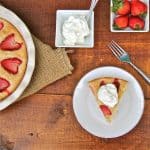 A piece of strawberry cake topped with whipped cream, and small dishes or strawberries and whipped cream.