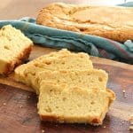 Several slices of tangerine sour cream pound cake on a cutting board, with a loaf of the cake in the background.