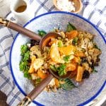 Tossed salad of oranges, cauliflower, kalamata olives, cashews and parsley, with a small bowl of feta cheese.