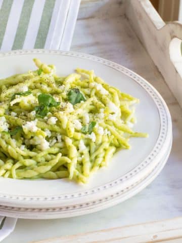 A plate of trofie twisted pasta tossed in a creamy poblano sauce topped with queso fresco cheese.