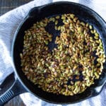 Pan-roasted pumpkin seeds in a cast iron skillet.