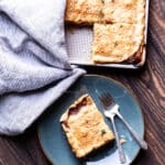 A cauliflower rarebit slab pie in a baking sheet, with one piece on a plate with a fork.
