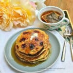A stack of blackberry cornmeal pancakes, drizzled with maple syrup.