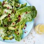 A salad of romaine lettuce, avocado, pine nuts, and pomegranate seeds, dressing a a lemon vinaigrette.