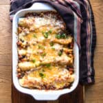 A casserole dish of vegetarian enchiladas, covered in melted cheese.