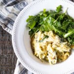 Asparagus egg bake with orzo and spinach in a bowl with a green salad.