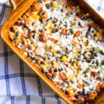Cheesy Mexican quinoa casserole with black beans and tomatoes in a baking dish.