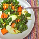 Kale salad with roasted sweet potatoes, apples and pepitas on a plate.