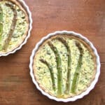 Two freshly baked asparagus quiche in quiche baking dishes.