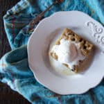 Chocolate chip cookie bar topped with a scoop of ice cream on a plate.