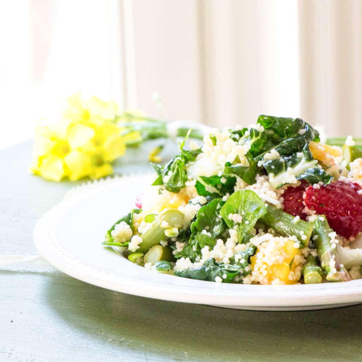 Side view of a baby bok choy salad with couscous, mango and strawberries.