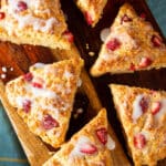 A close up of strawberry oat scones on a cutting board, with icing.