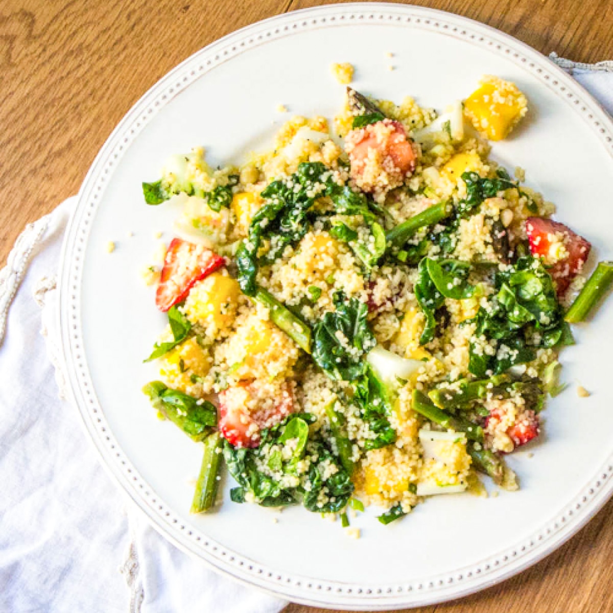 Top view of a baby bok choy salad with couscous, mango and strawberries.