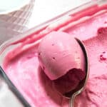 Plum frozen yogurt being scooped up with a spoon.