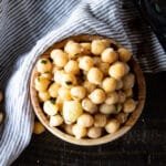 A wooden bowl of cooked chickpeas.