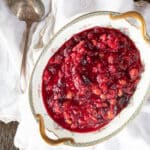A serving dish filled with cranberry pear sauce with a serving spoon.