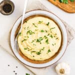 Red skin mashed potatoes in a serving bowl with a fork.