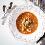 A bowl of homemade vegetable soup with 2 spoons.