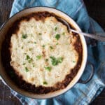 Shepherd's pie made with lentils and topped with mashed potatoes with a serving spoon.