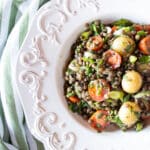 Potato and lentil salad with tomatoes, scallions, and oregano in a white bowl.