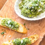 Mashed fava bean dip in a bowl and spread on toasts for a crostini appetizer.