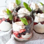 Glasses filled with layers of berries and cream topped with chocolate shavings and mint.