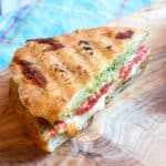 One half of a sliced caprese panini on a cutting board.