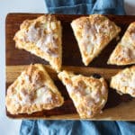 Glazed peach scones on a cutting board and a blue napkin.
