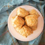 A pile of cheddar and herb biscuits heaped on a white plate.