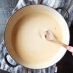 A wide-mouthed pan of Stouffer's Welsh Rarebit cheese sauce with a wooden spoon.