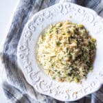 A white pasta bowl filled with lemony orzo and asparagus with breadcrumbs.